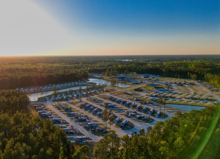 Aerial view of Savannah Lakes RV Resort with rows of RV sites, lakes, and surrounding trees at sunset